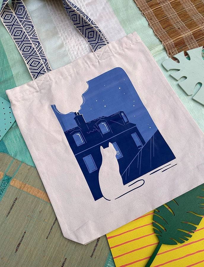 Grand totebag fabriqué en matières recyclées et imprimé en France représentant un paysage nocturne paisible. Ambiance calme d'une ville de nuit, avec un chat qui regarde les toits.