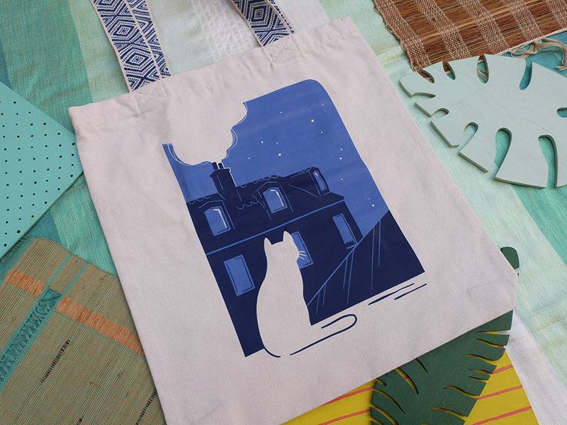 Grand totebag fabriqué en matières recyclées et imprimé en France représentant un paysage nocturne paisible. Ambiance calme d'une ville de nuit, avec un chat qui regarde les toits.